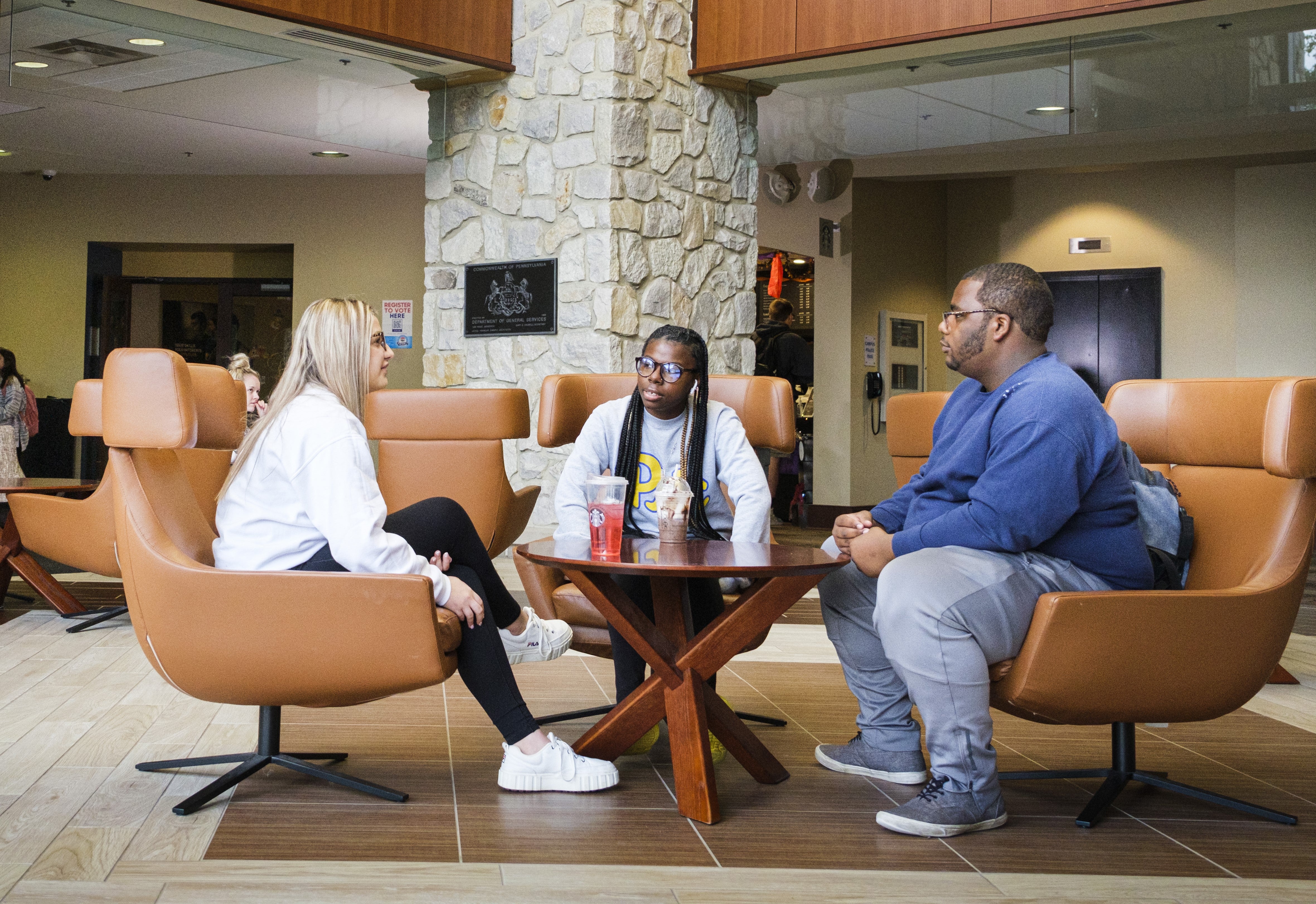 Students sitting at chairs conversing while sitting in the lobby of Blackington Hall. 