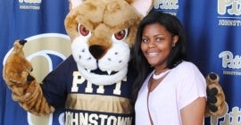 student standing next to Pitt Johnstown mascot
