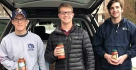 three students holding pasta sauce