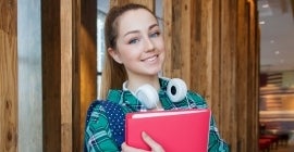 student with books and headphones smiling 