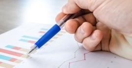 pen pointing to graphs on paper