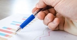 pen pointing to graphs on paper 