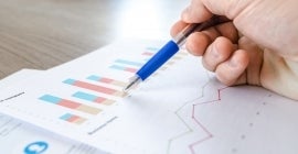 pen pointing to graphs on paper 