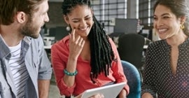 three students smiling looking at a tablet